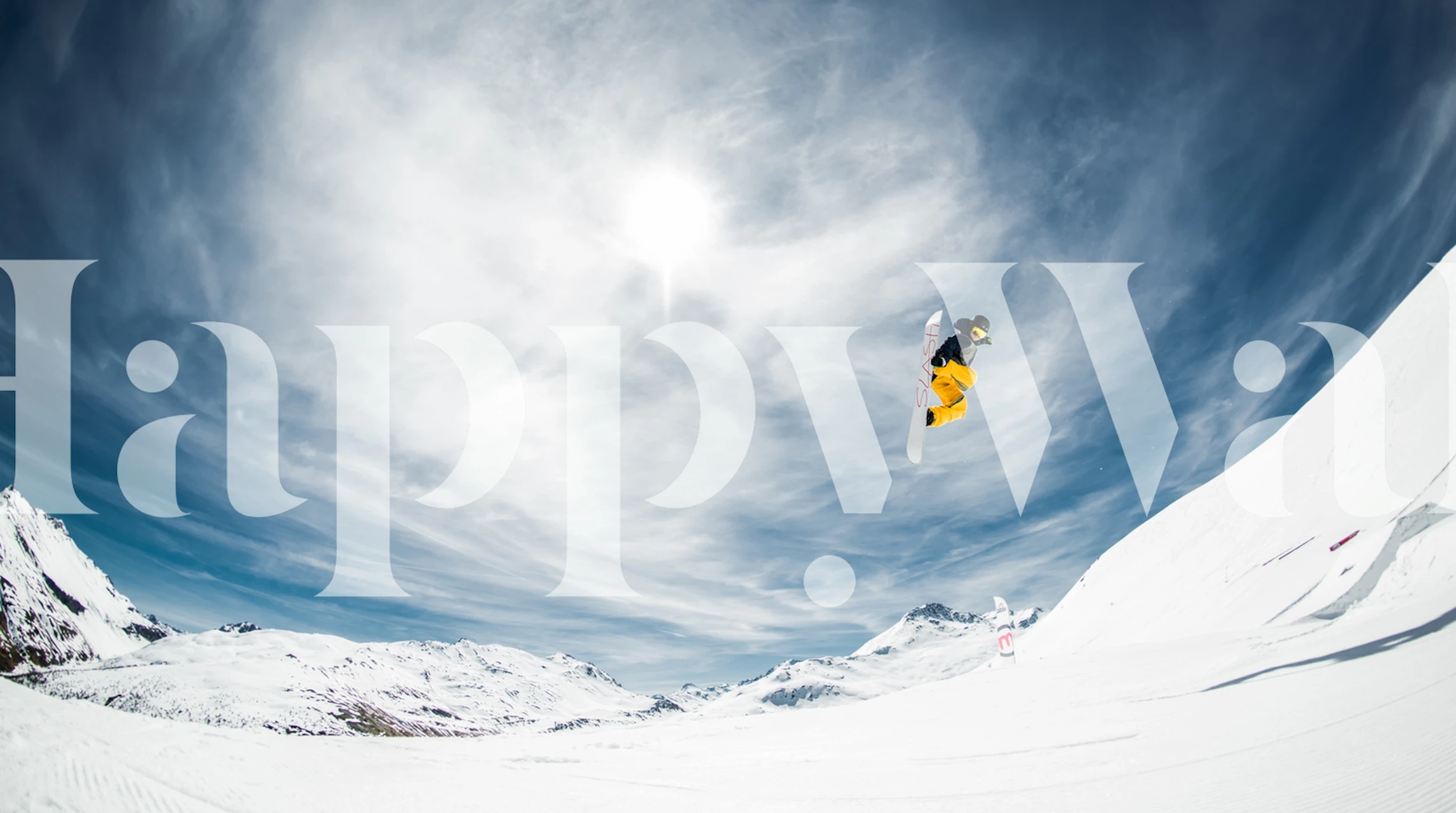 Snowboarder performing a jump in a snow-covered mountain landscape wallpaper