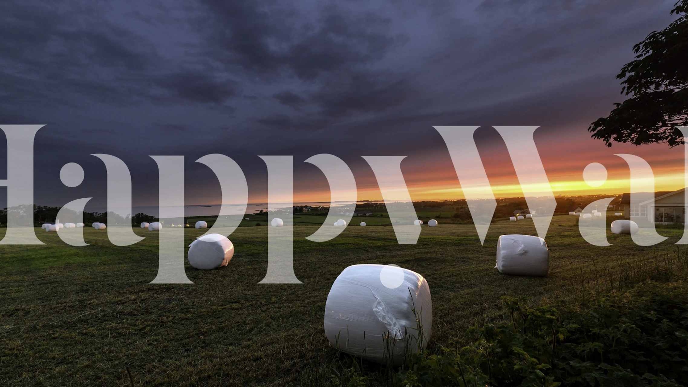 Maaseudun viljelysmaa auringonlaskun aikaan heinäpaalien seinämaalauksella