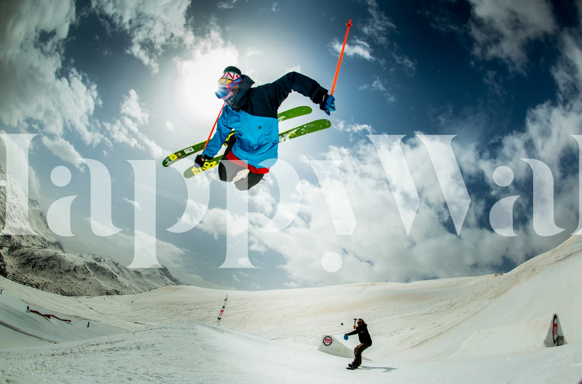 Skier performing tricks in bright blue outfit against a snowy backdrop wallpaper