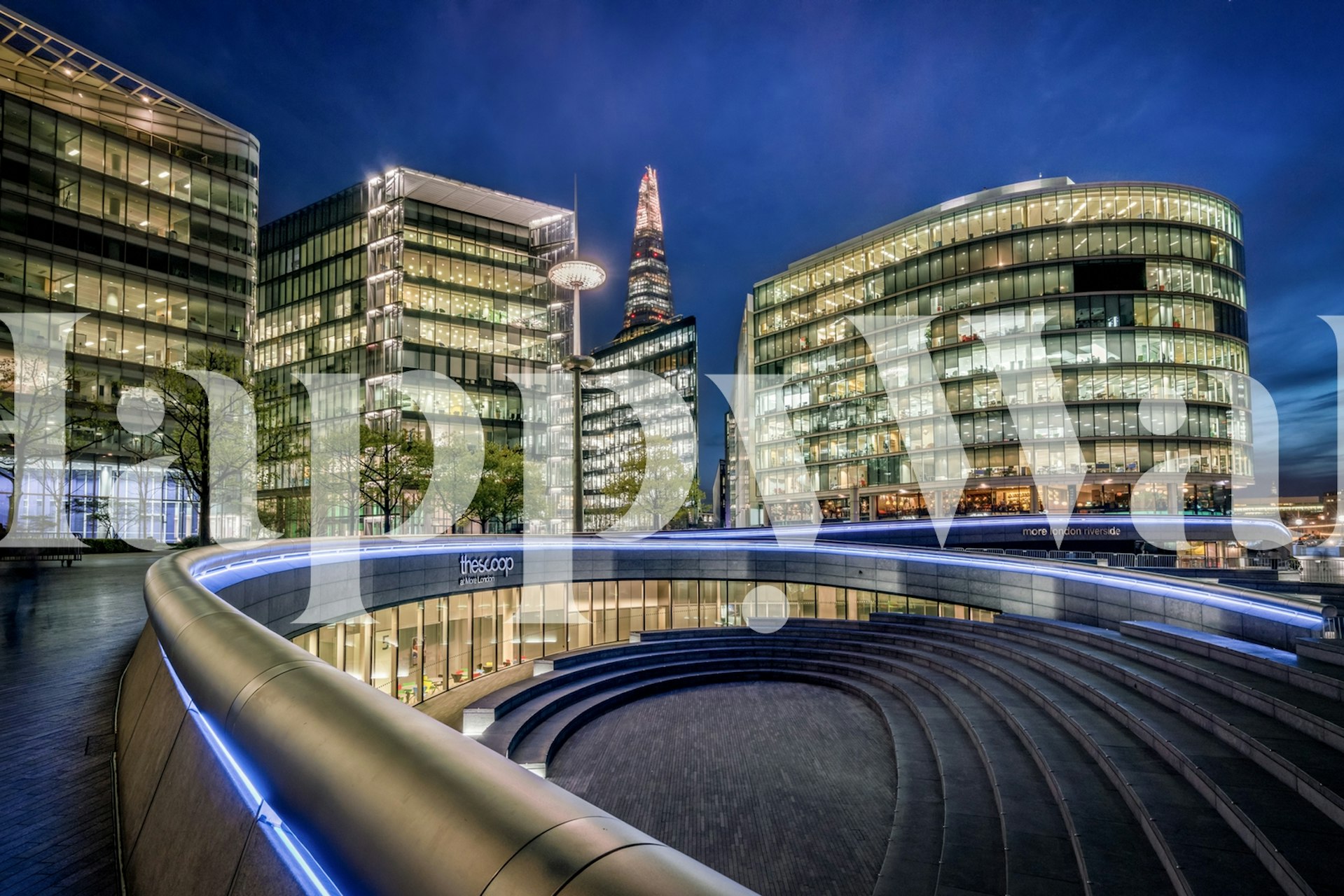 Modern cityscape at night with glass buildings and blue lights wallpaper