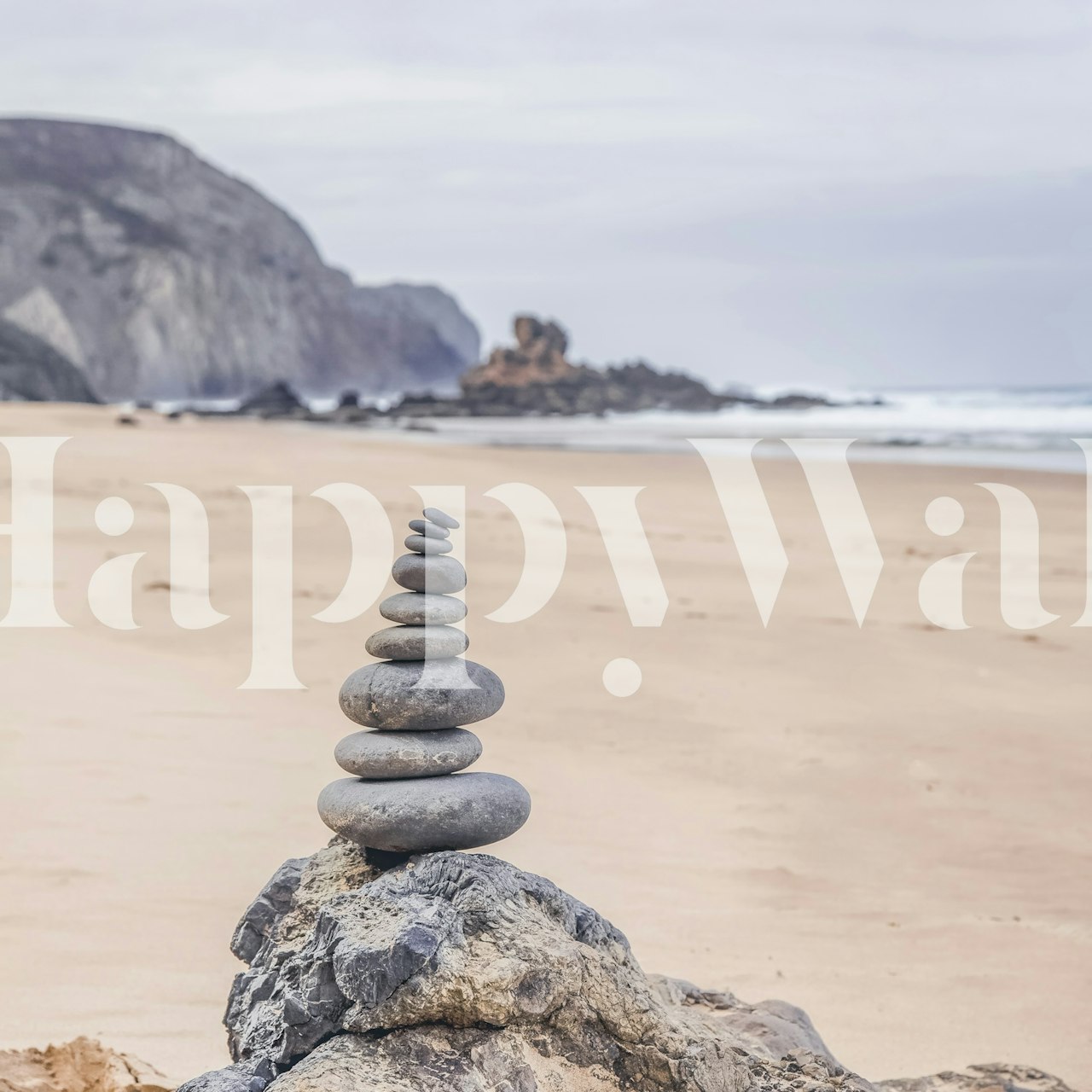 Zen-inspired pebble stack wall mural on a tranquil Portuguese beach with sandy shores and misty cliffs