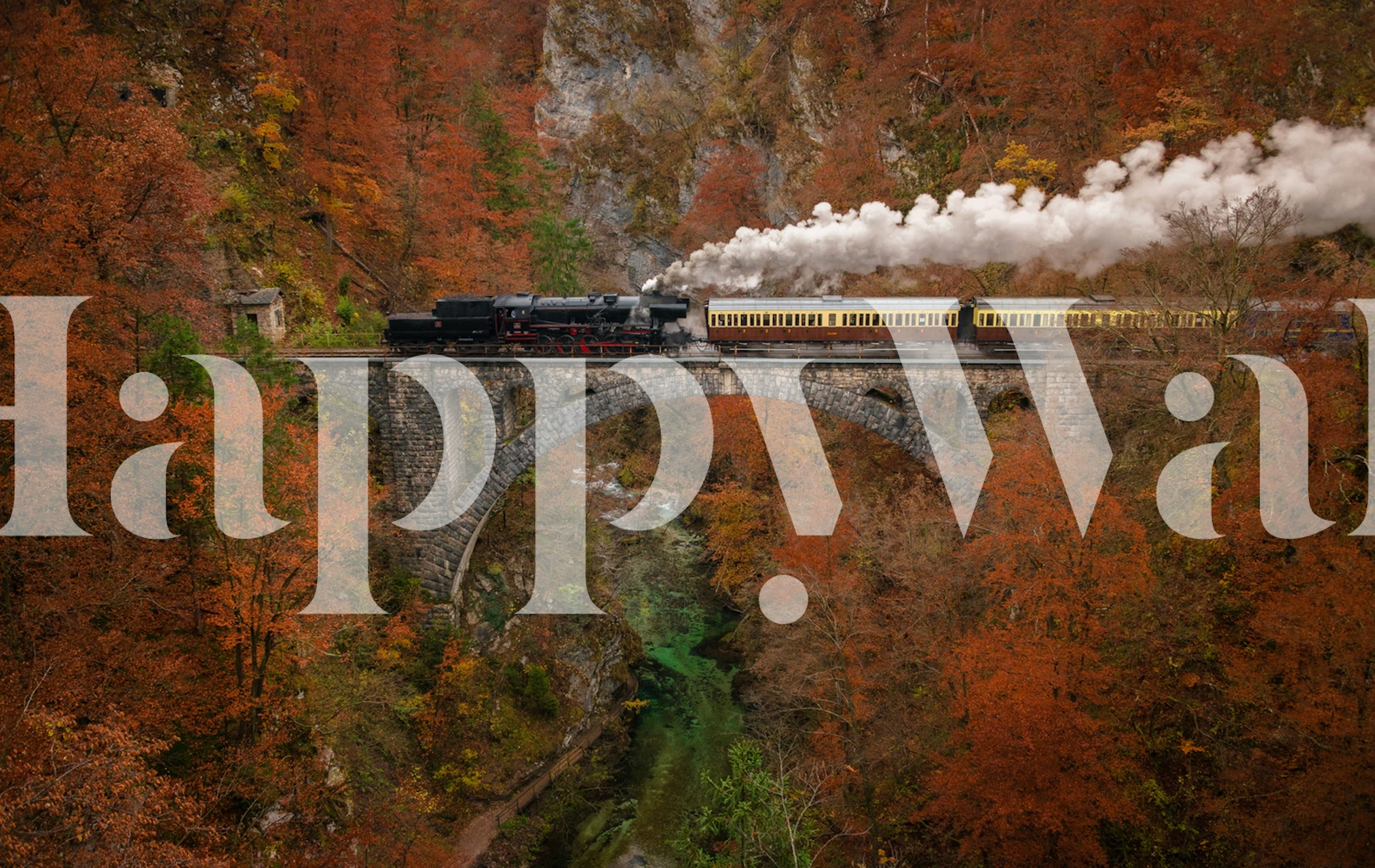 Train crossing a stone bridge in vibrant autumn colors wallpaper