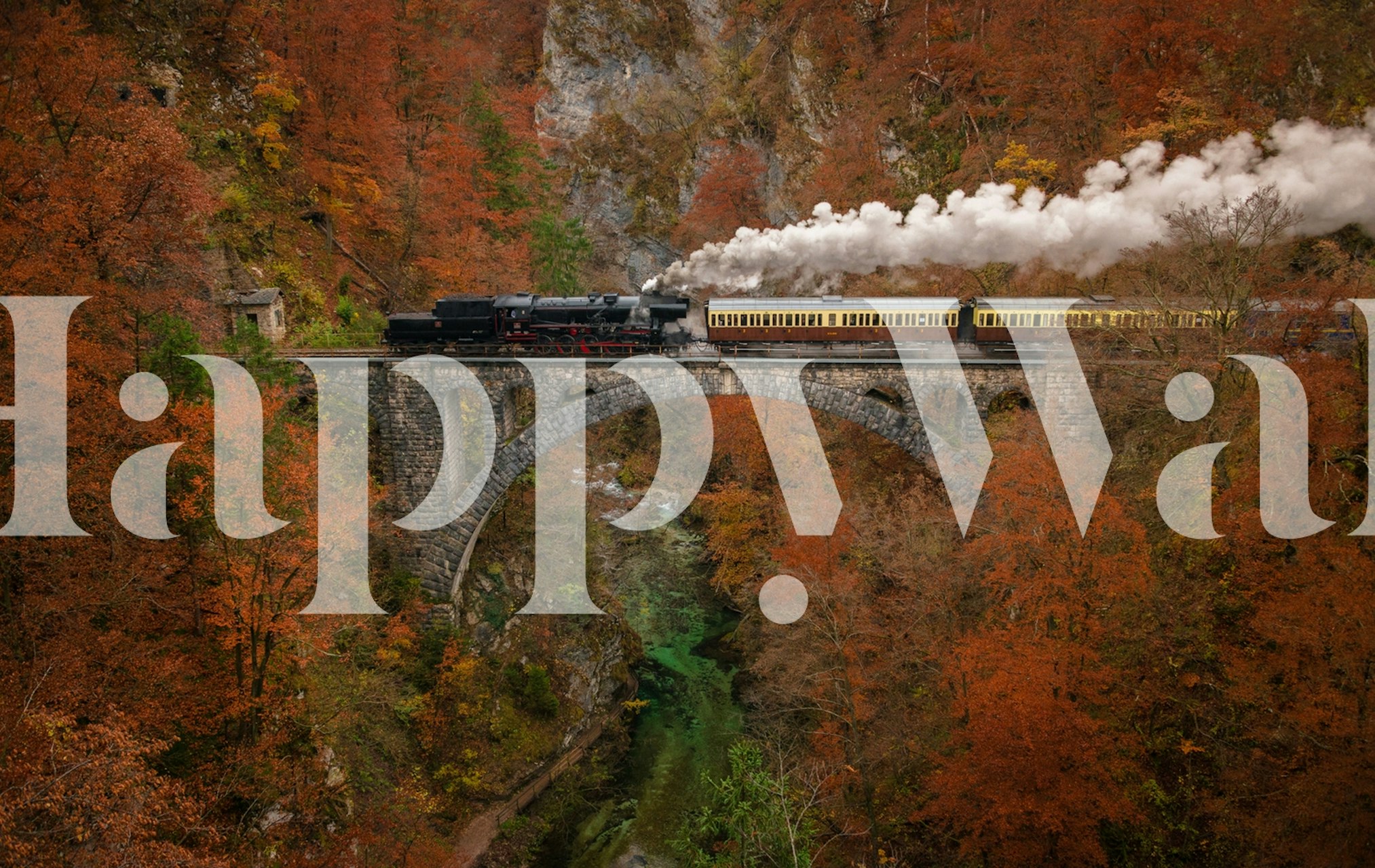 Train crossing a stone bridge in vibrant autumn colors wallpaper