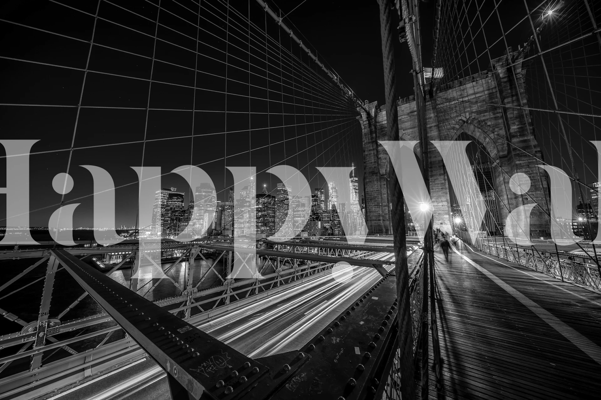 Black and white wall mural of the Brooklyn Bridge at night with city lights