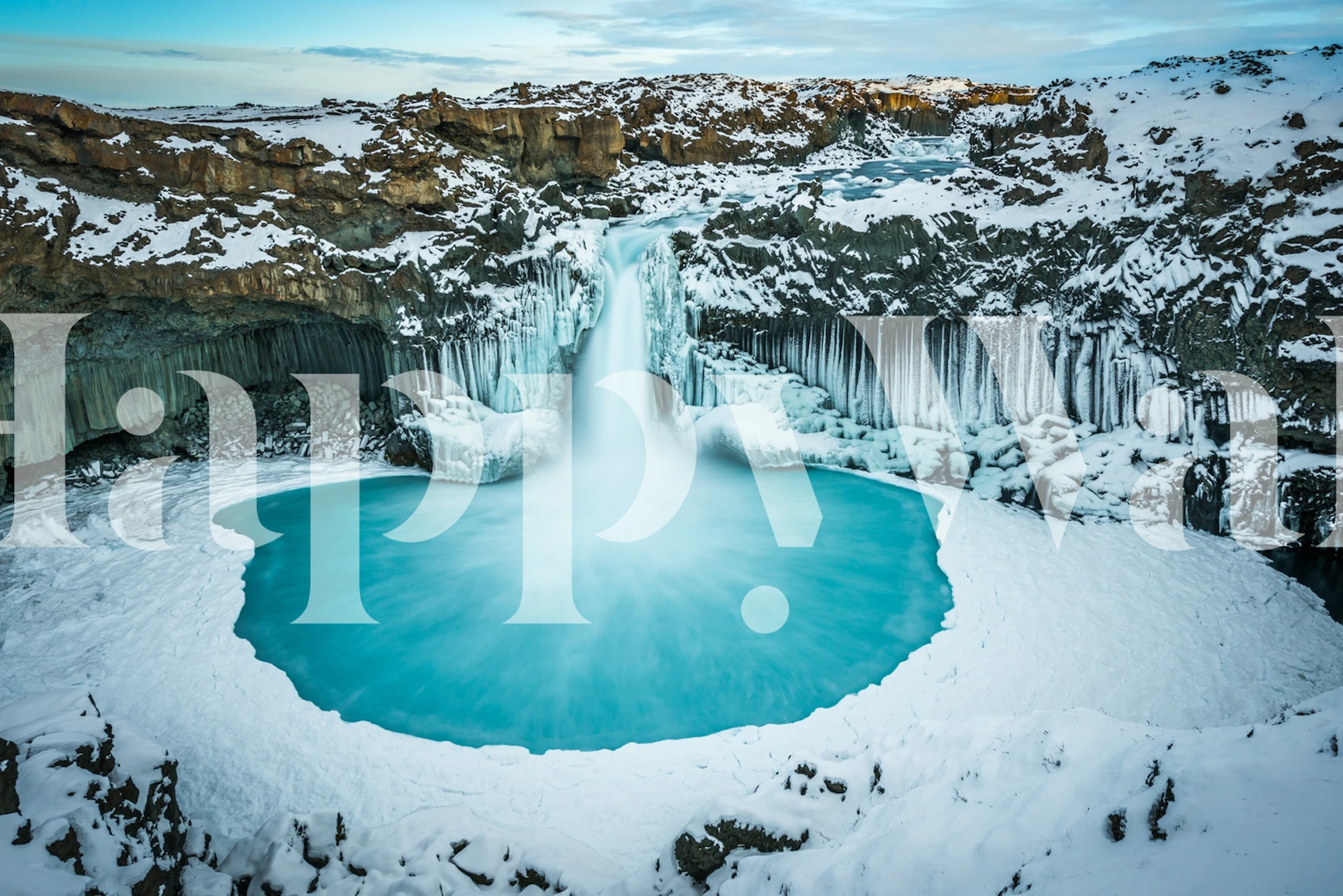 Azure blue waterfall cascading into a frozen lake wallpaper