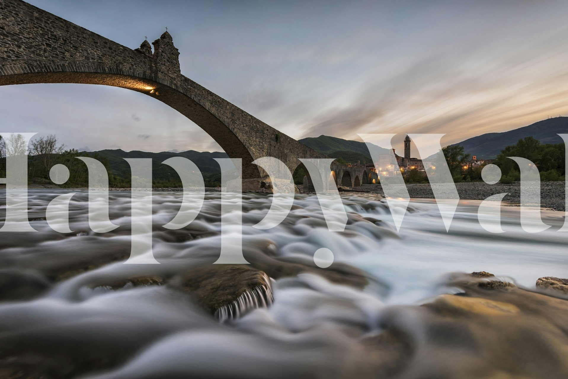 Time-worn bridge over a serene river at dusk wall mural