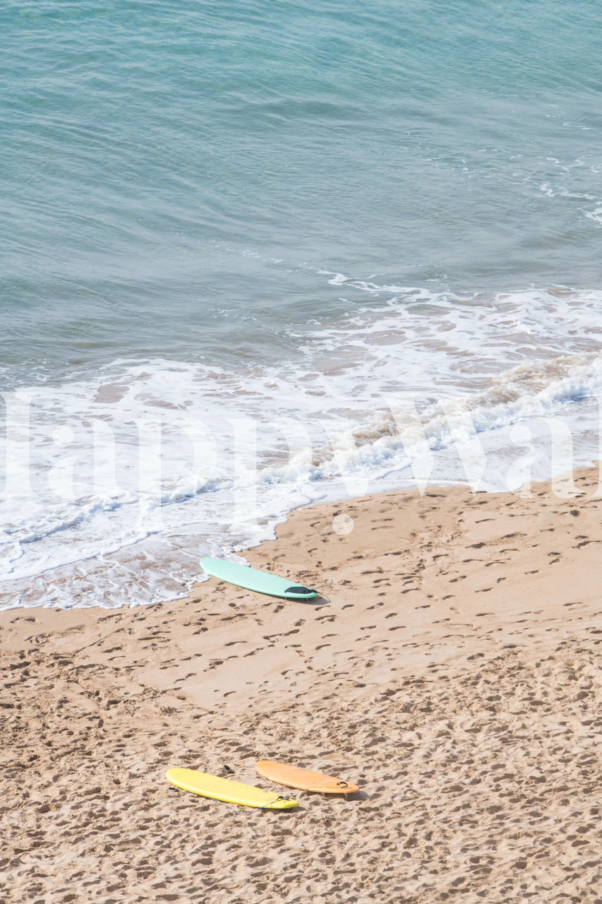 Surfboards in soft colors on sandy beach with ocean wallpaper