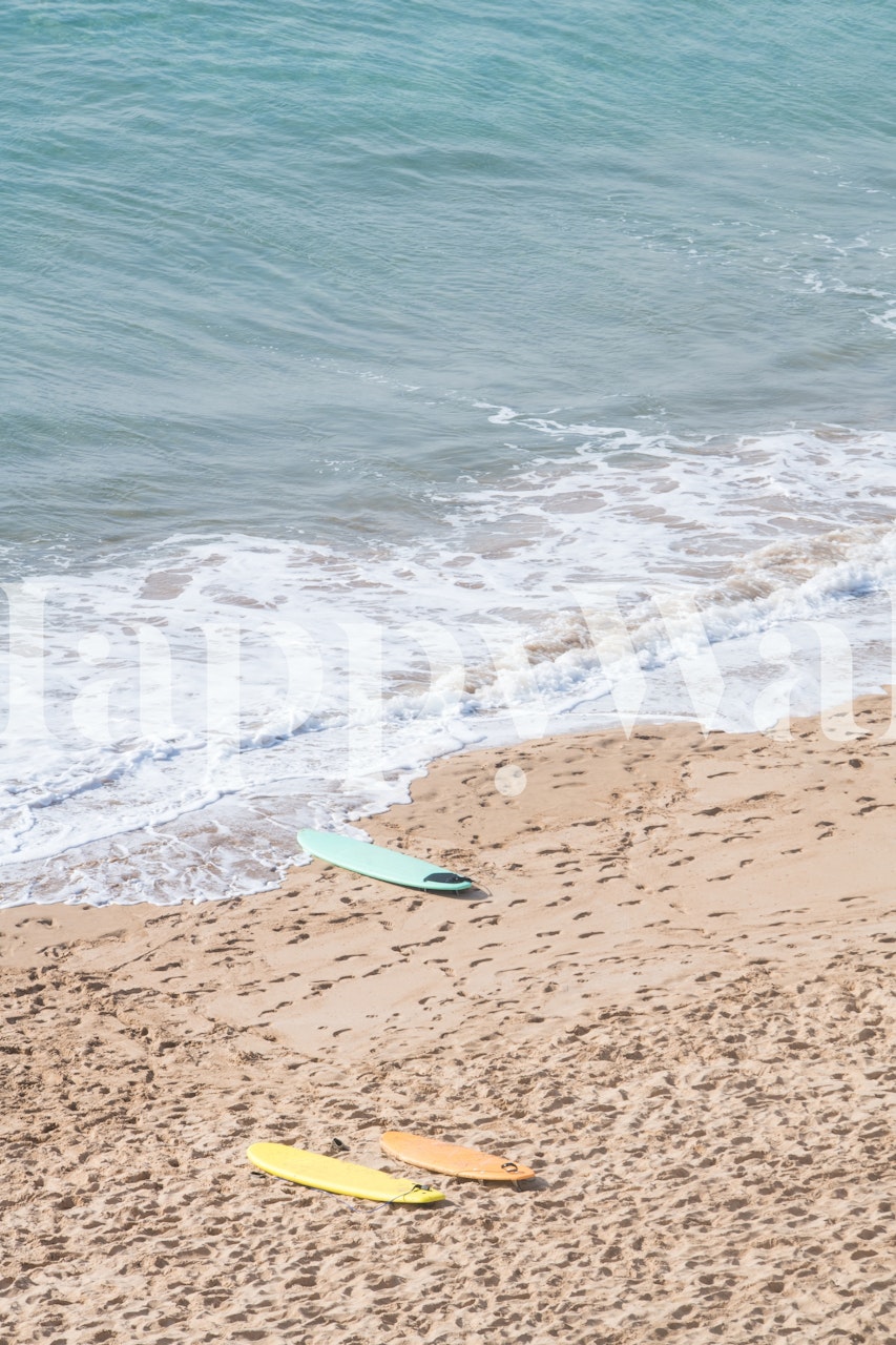 Surfboards in soft colors on sandy beach with ocean wallpaper