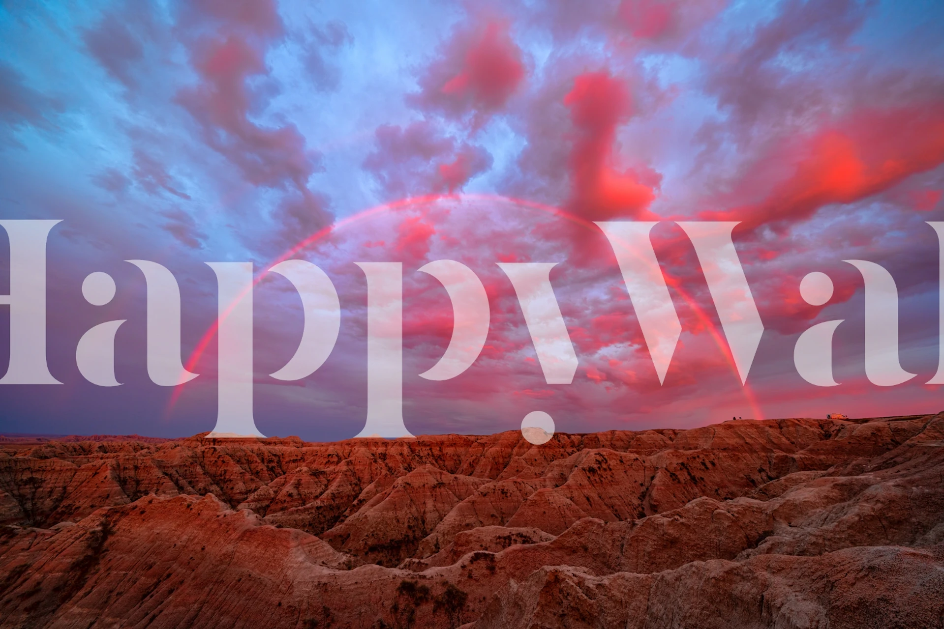 Wall mural of the Badlands with a vibrant sunset and rainbow arc in the sky