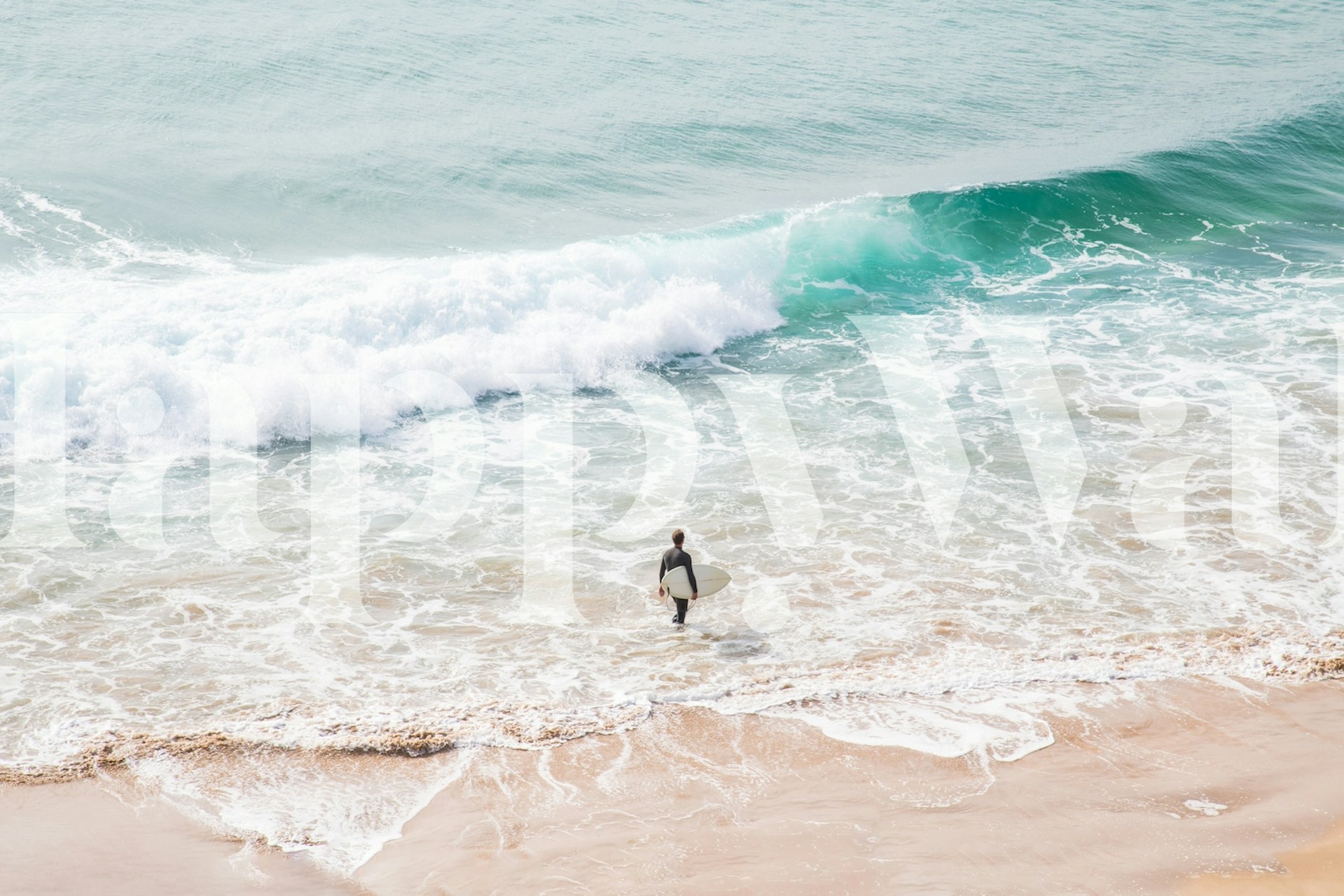 Surfer walking towards turquoise waves on sandy shore wallpaper