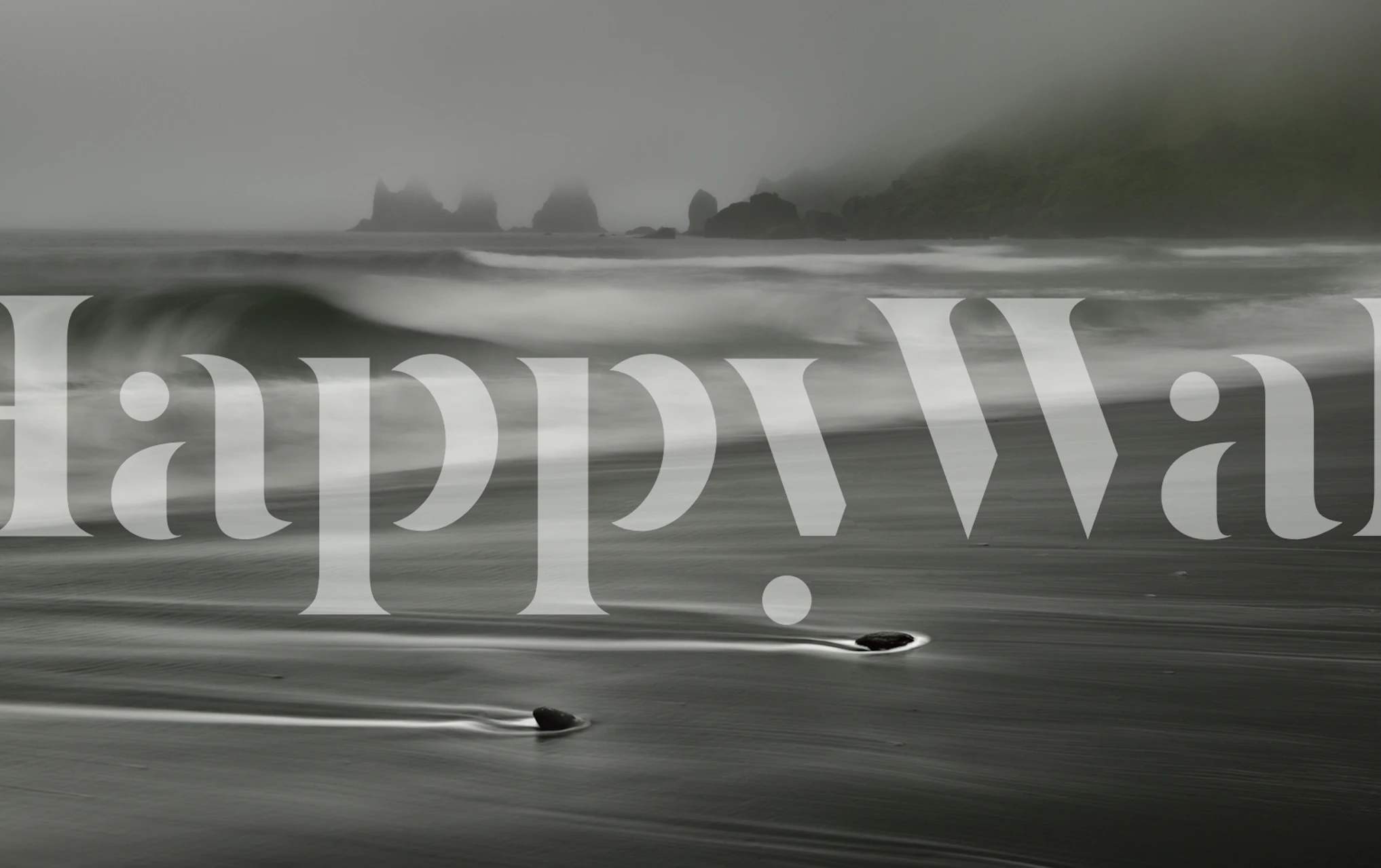 Black and white beach scene with smooth waves and rocks wallpaper