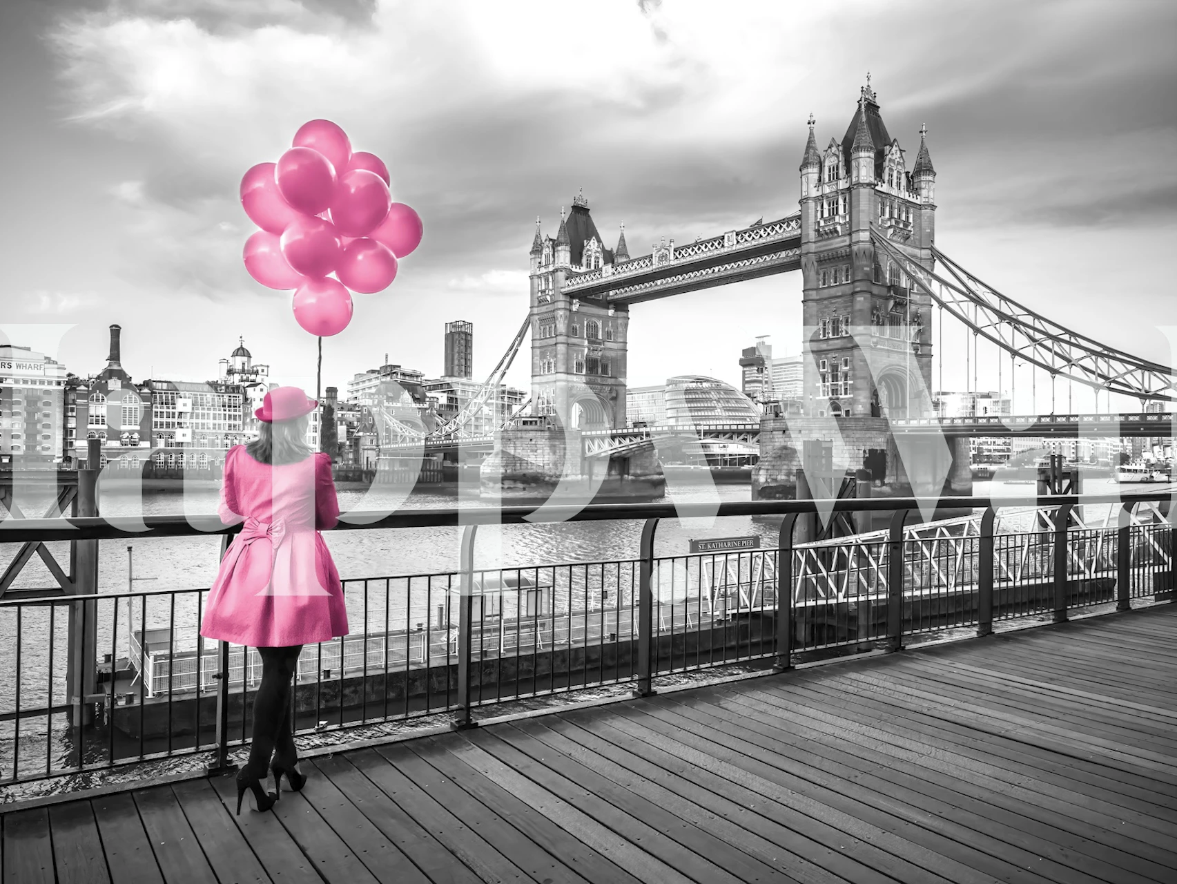 Woman in pink coat holding pink balloons with London Bridge in black and white wallpaper
