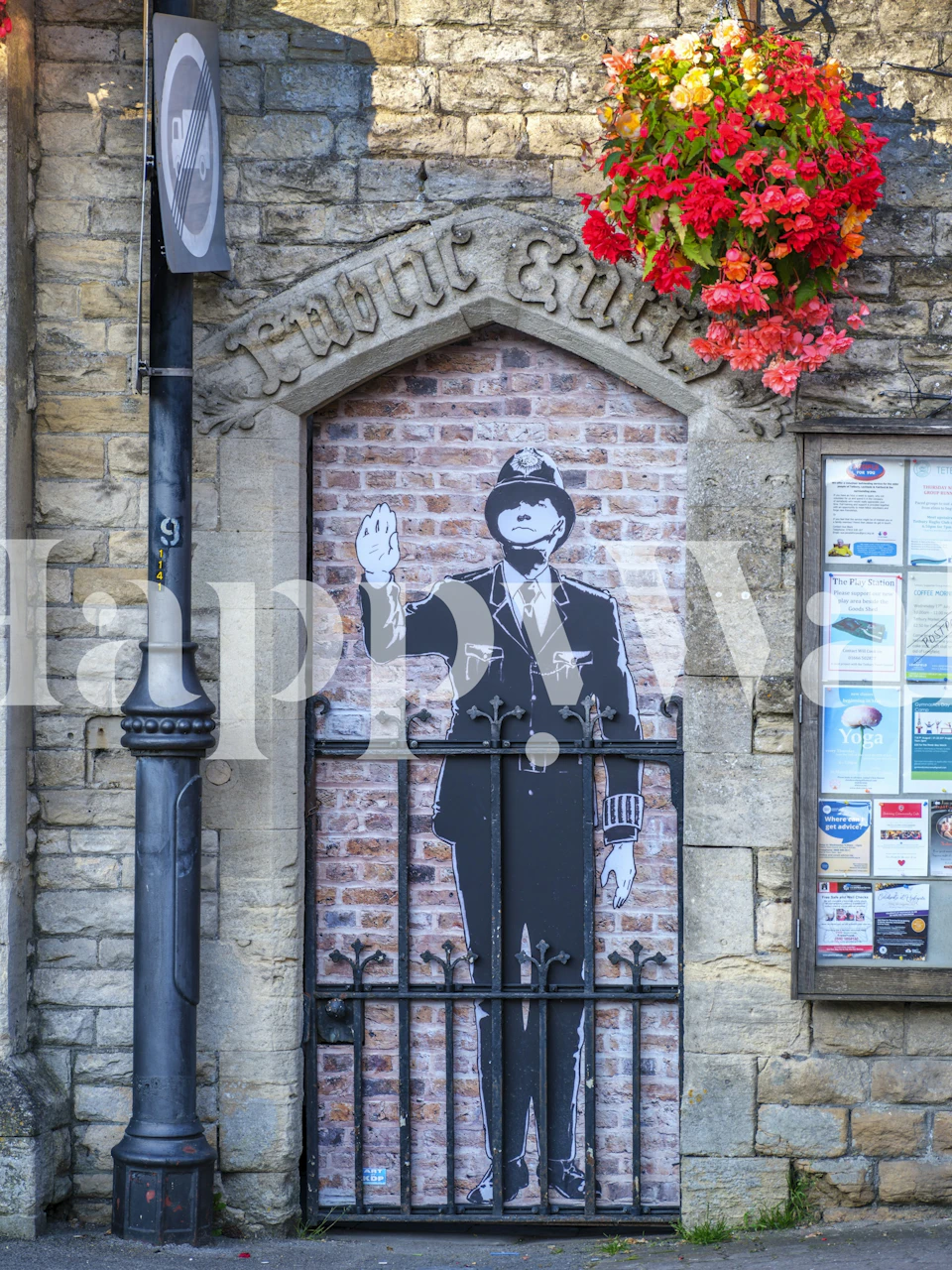 Cotswold village wall mural with a faux guard figure and floral accents