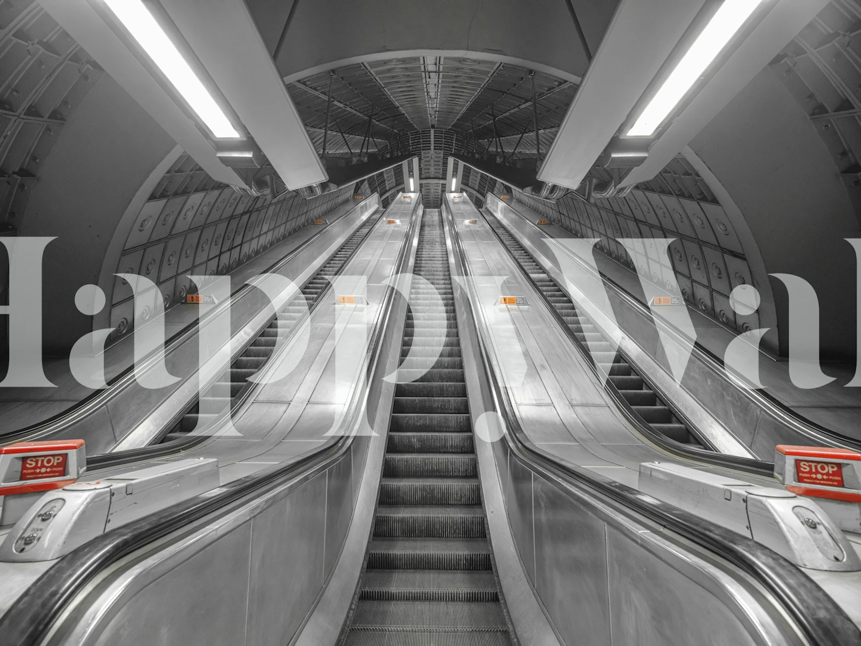 Black and white wall mural of subway escalators leading upwards in a symmetrical pattern