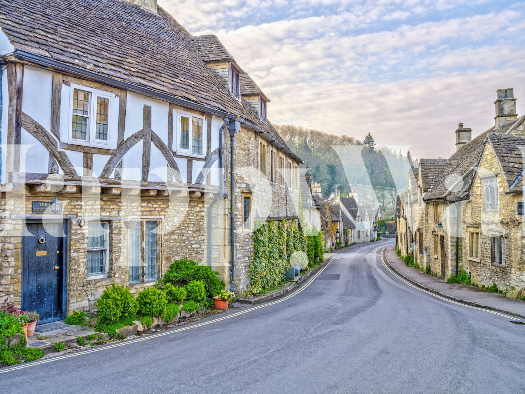 Traditional European village street with stone cottages and floral accents.