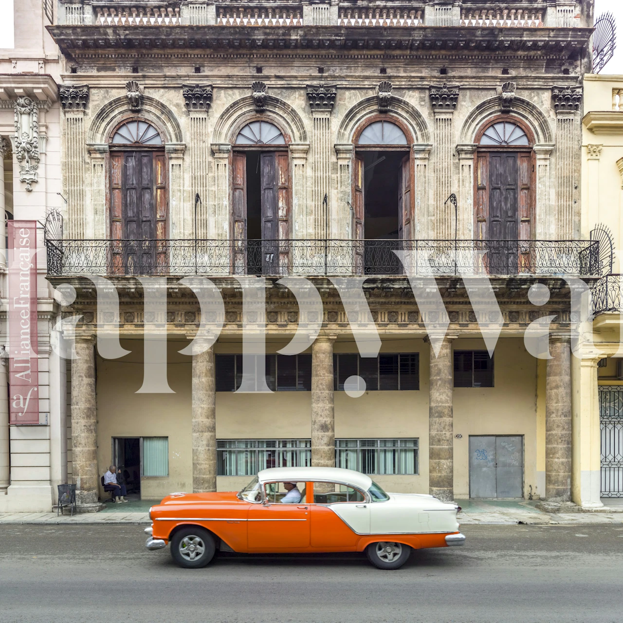 Vintage car in orange and white against historic architecture wallpaper