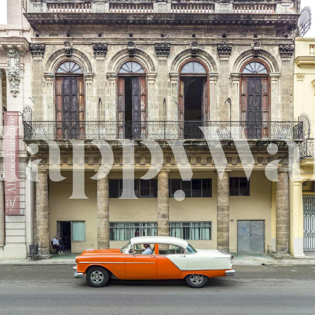 Vintage car in orange and white against historic architecture wallpaper