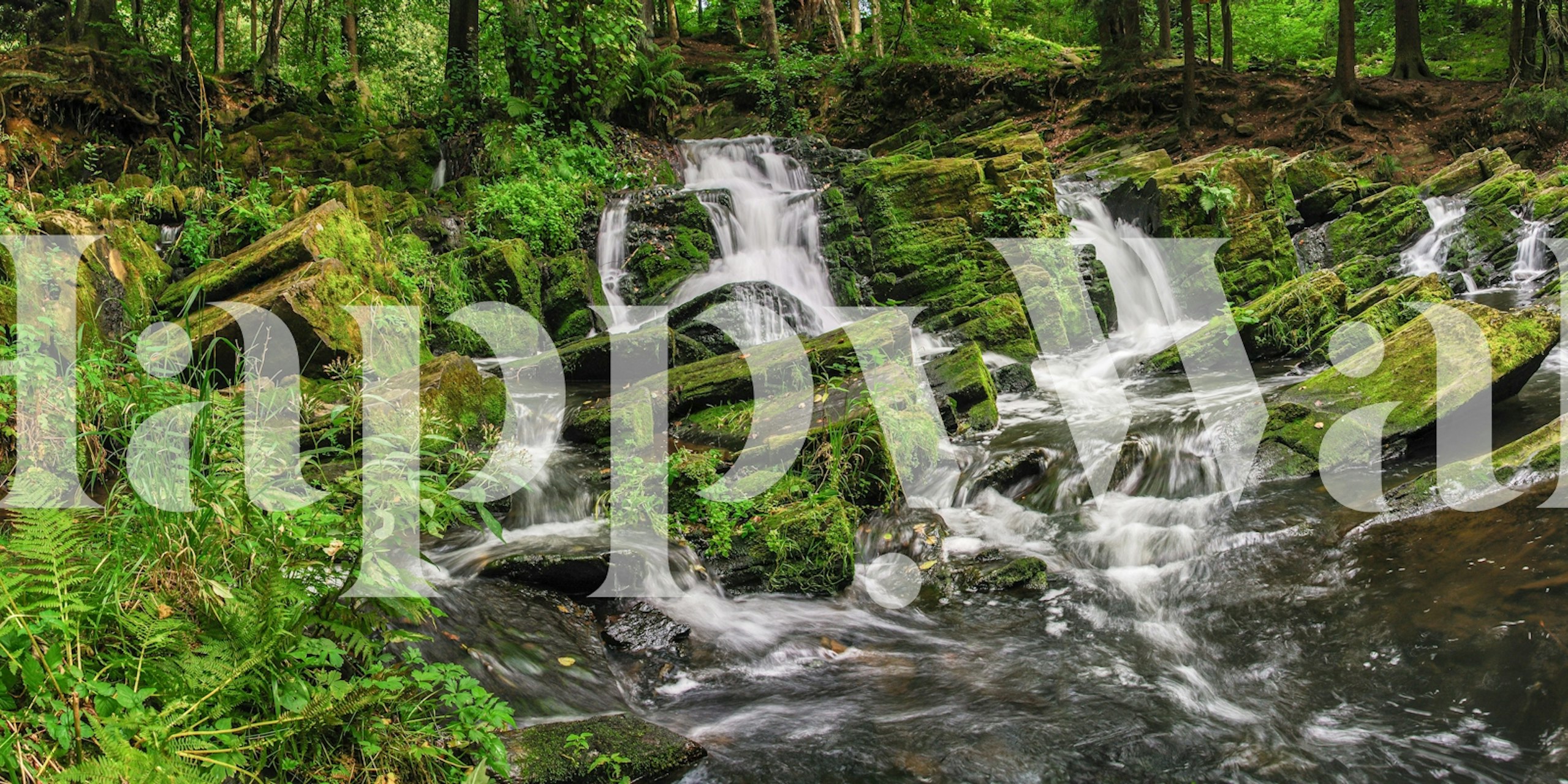 Lush green waterfall scene with flowing water and rocks wallpaper