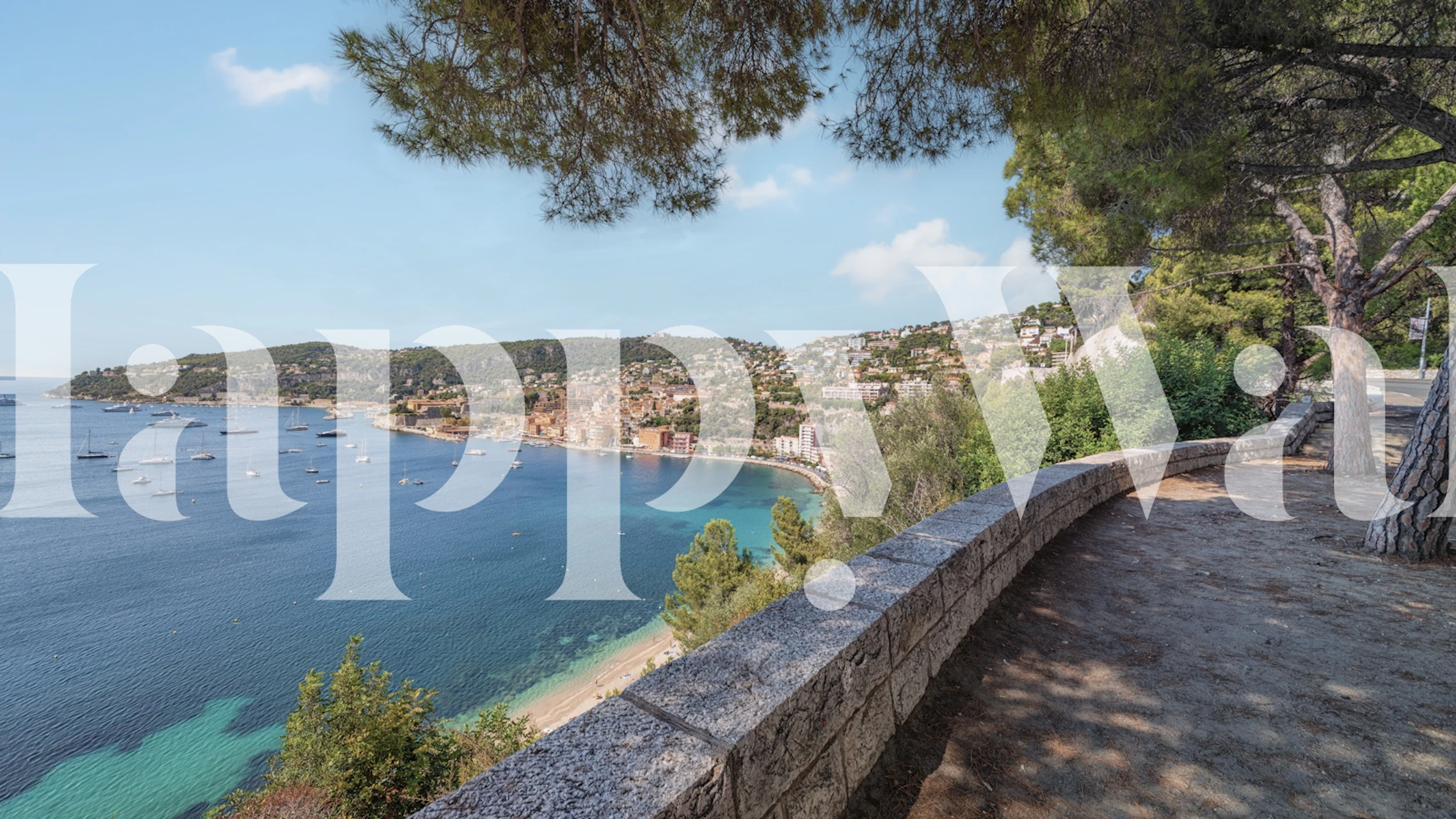 A scenic coastline wall mural of the French Riviera with an ocean view, promenade, and lush trees