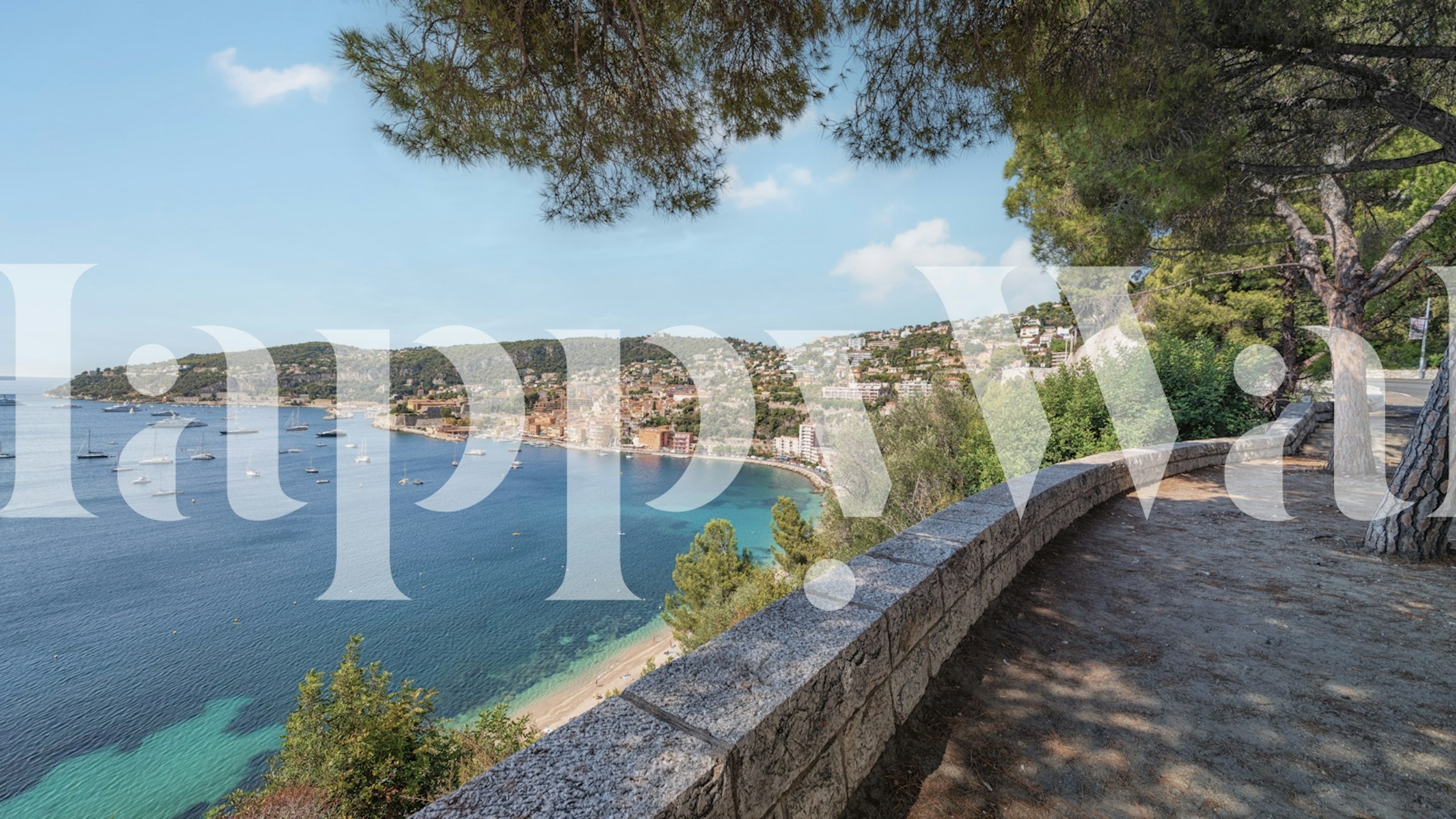 A scenic coastline wall mural of the French Riviera with an ocean view, promenade, and lush trees